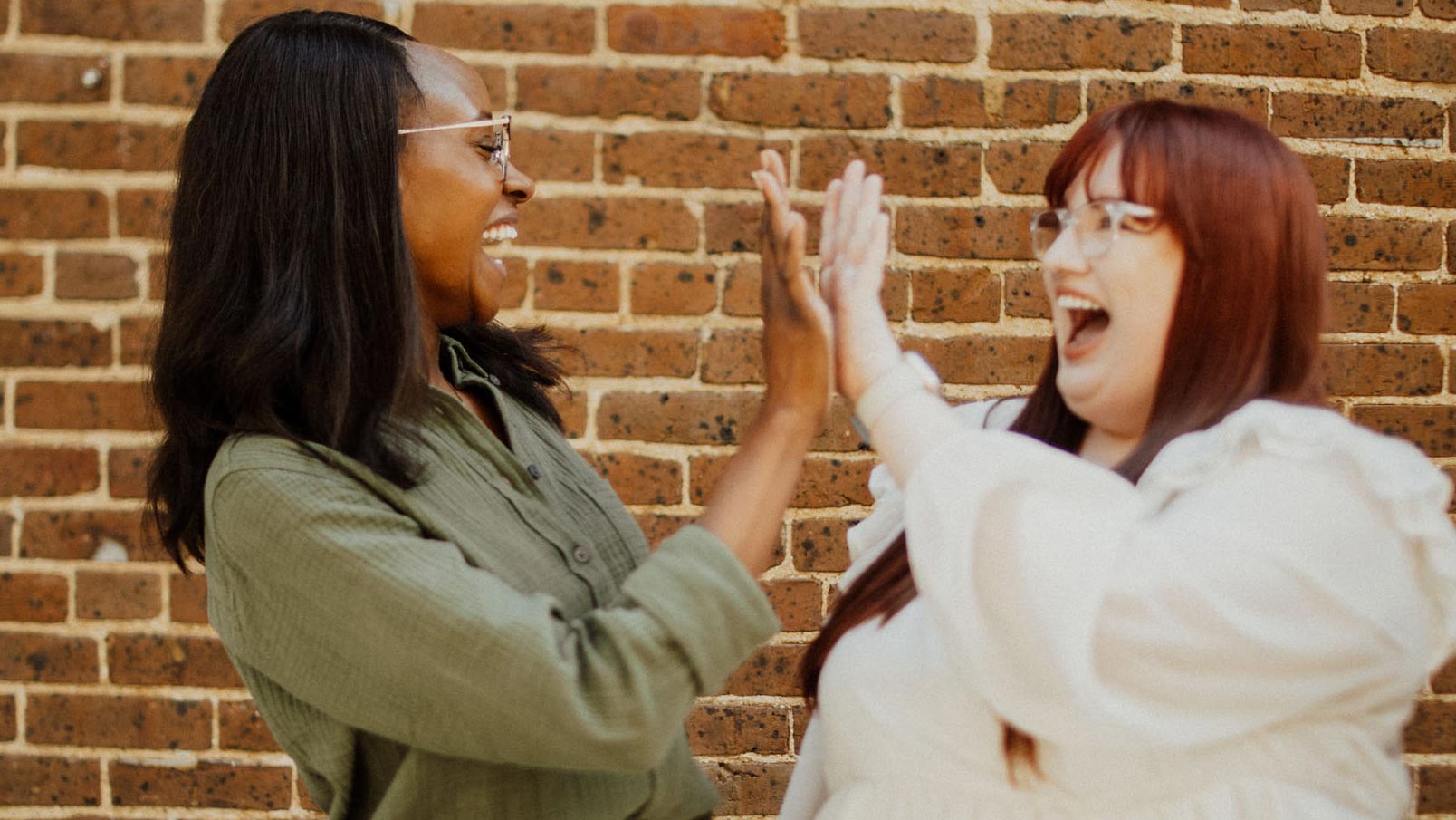 two women high fiving symbolising the good benefits working at the brave fight