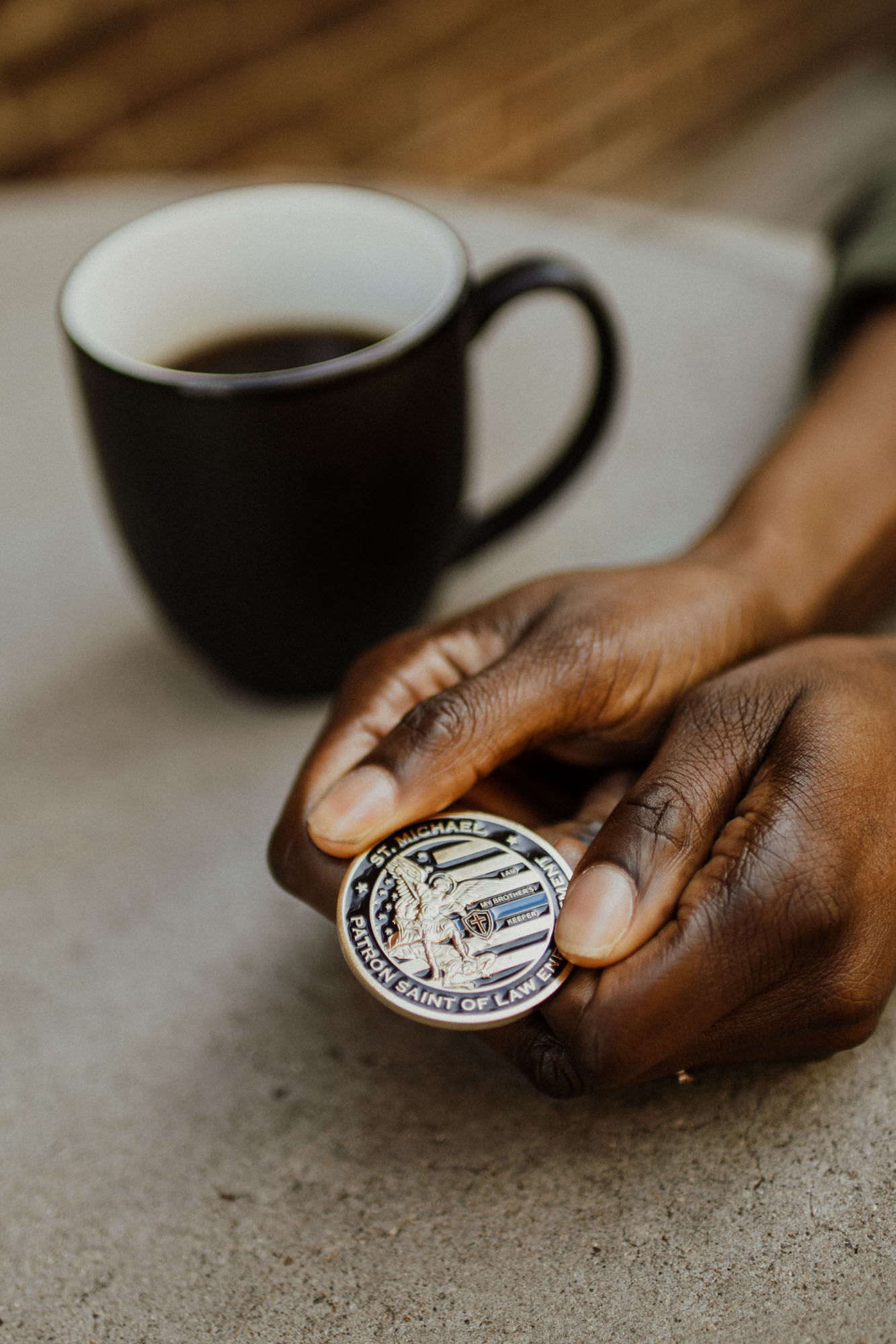 hands holding patron saints of law enforcement coin fort worth