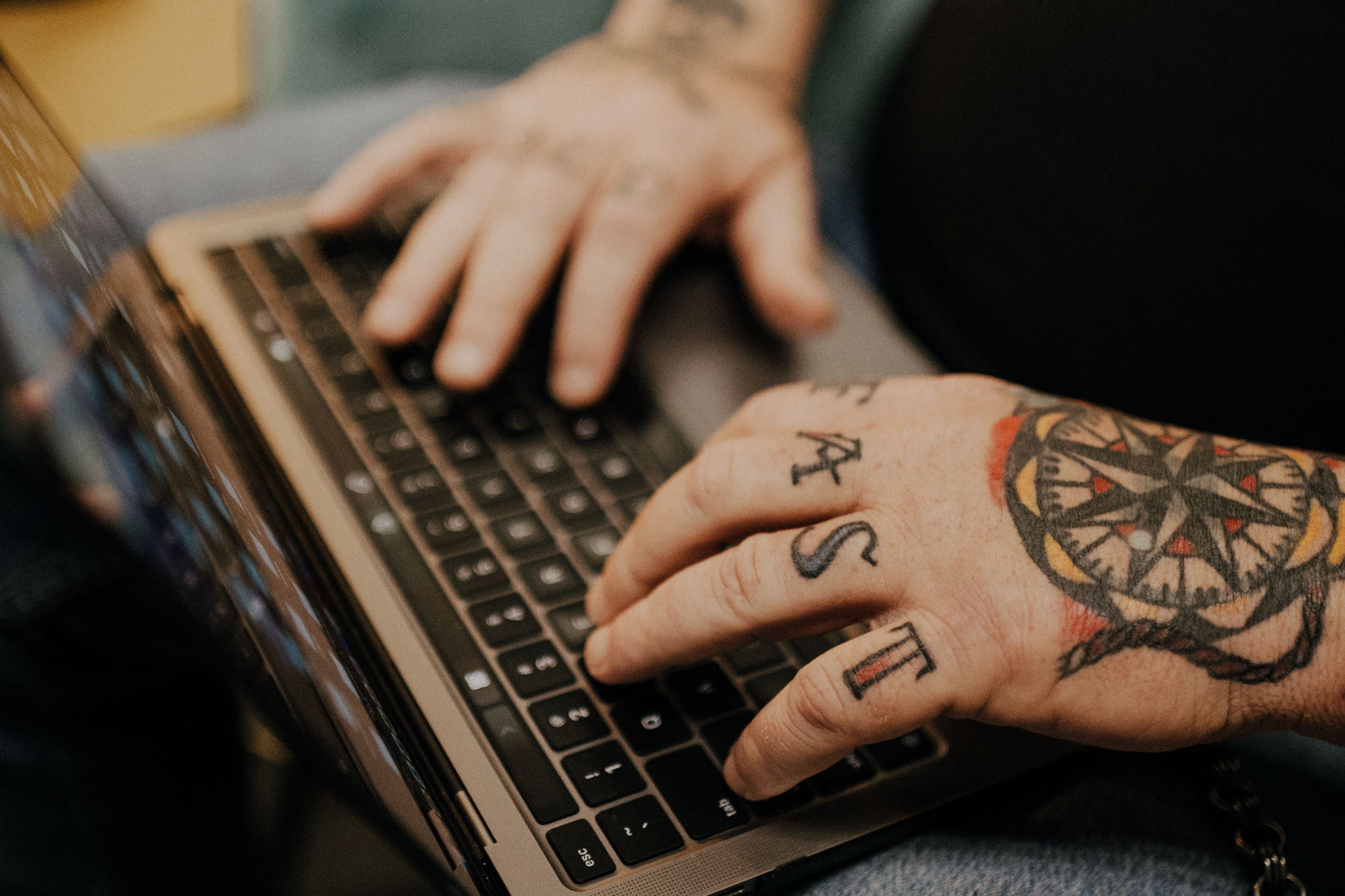 hands with tattoos typing on a computer