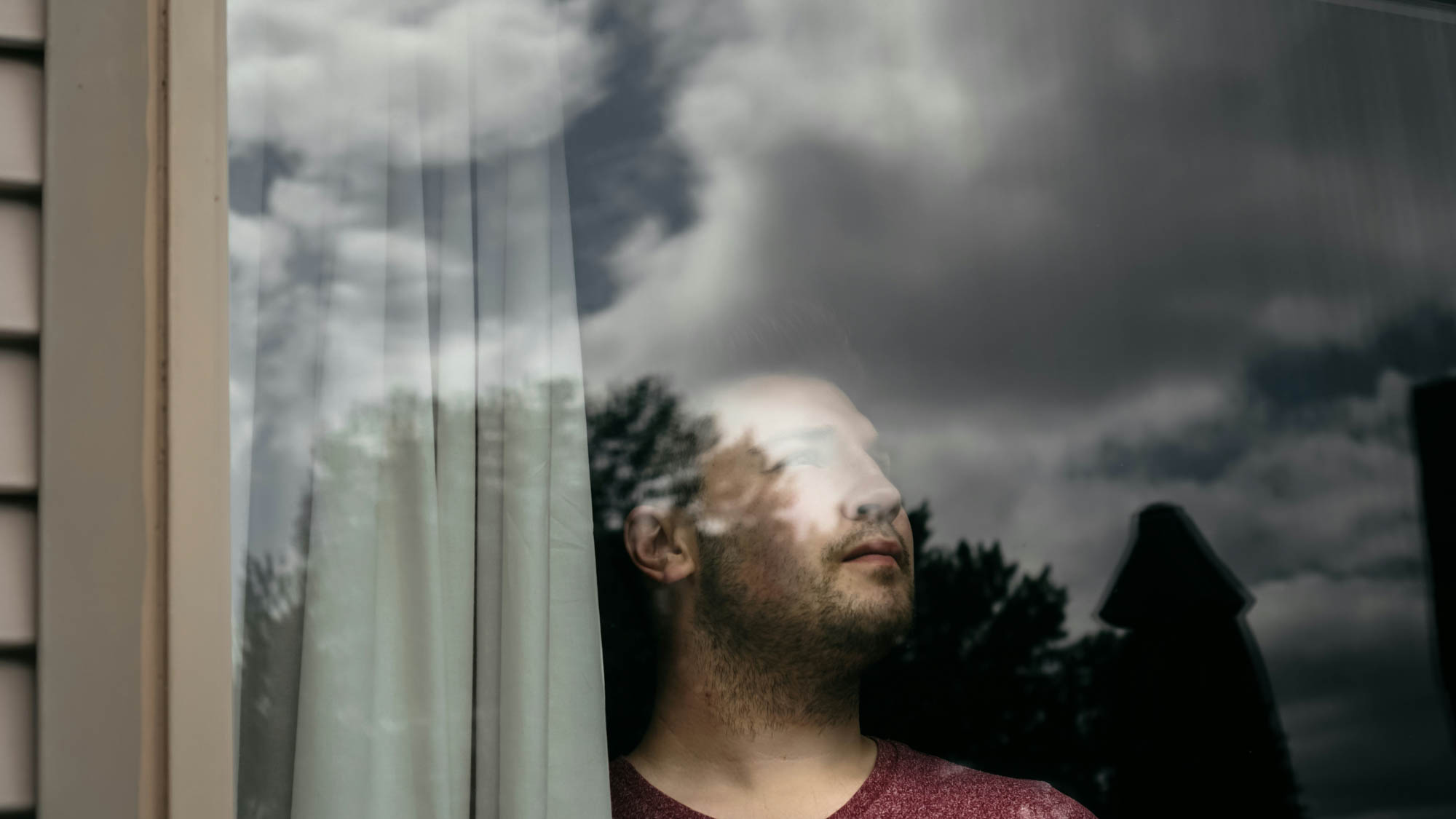 man looking out of window for better days