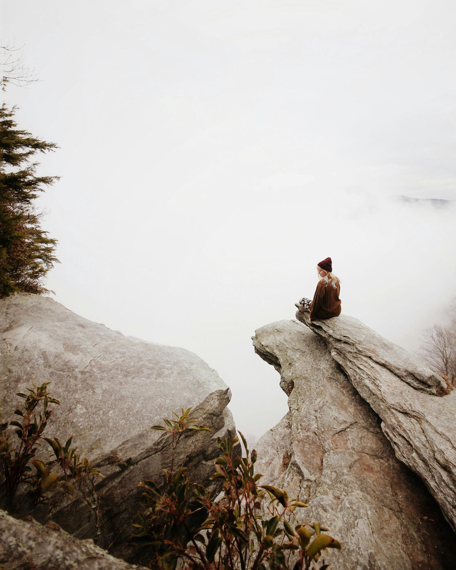 woman sitting on a rock and there are clouds